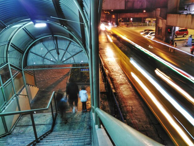 Sentieri di luce sulla strada con persone che camminano a gradini durante la notte