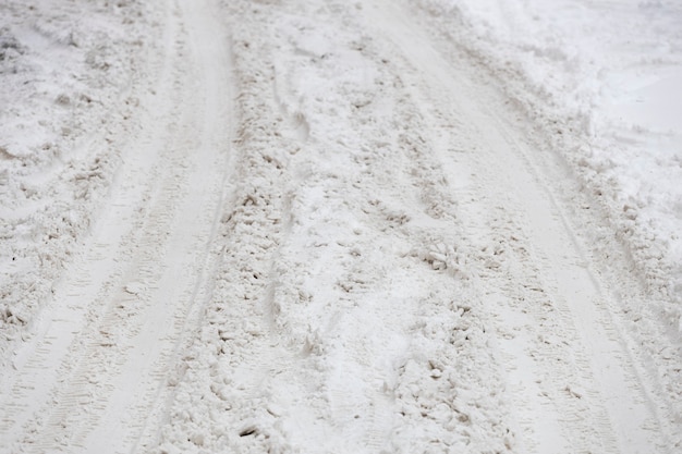 Sentiero da pneumatici per auto nella neve. strada invernale non ritirata. Foto di alta qualità