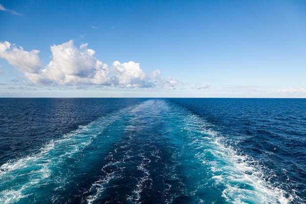 Sentiero dal movimento della nave in mare che si estende all'orizzonte con un cielo limpido con nuvole