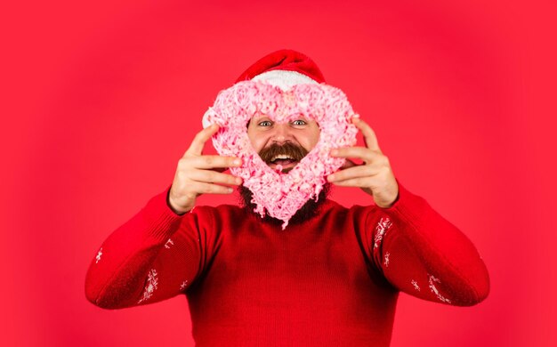 Sentimenti reali regali e regali sorpresa di preparazione per le vacanze di Natale festa di capodanno hipster maturo e brutale con cappello di Babbo Natale è il periodo natalizio uomo barbuto felice in maglione