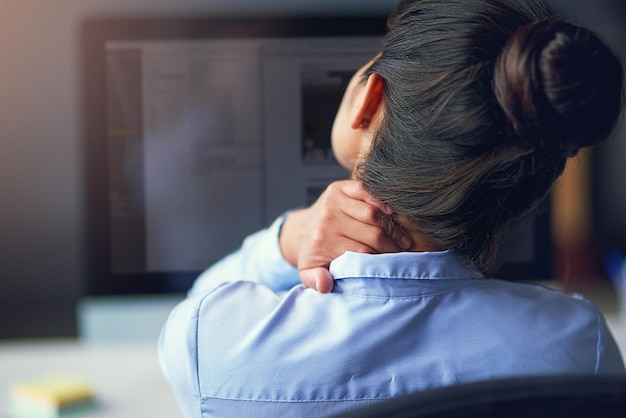 Sentire lo sforzo Inquadratura posteriore di una donna d'affari che soffre di dolore al collo in ufficio