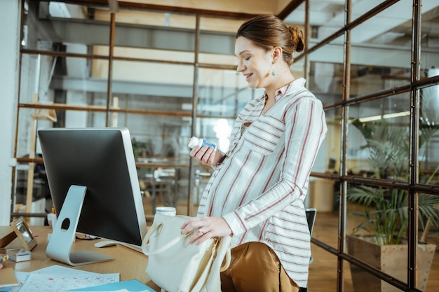 Sentirsi bene. Elegante donna d'affari che si sente davvero eccitata e buona mentre assume vitamine