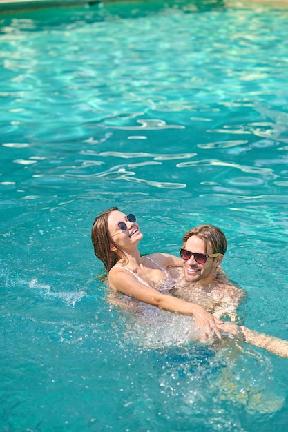 Sentirsi bene. Giovani coppie che nuotano in una piscina e che si sentono eccitate