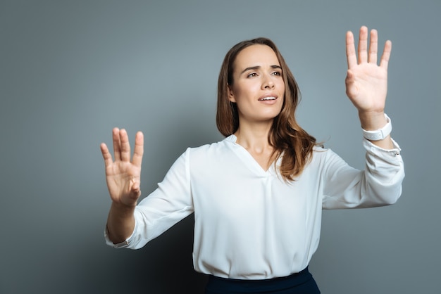 Sentirsi eccitati. Allegro bella giovane donna in piedi su sfondo grigio e guardando le sue mani mentre si sente eccitato