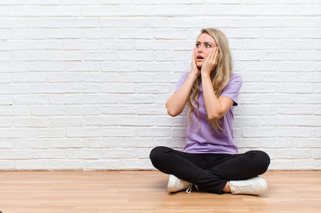 sentirsi felici, eccitati e sorpresi, guardando di lato con entrambe le mani sul viso