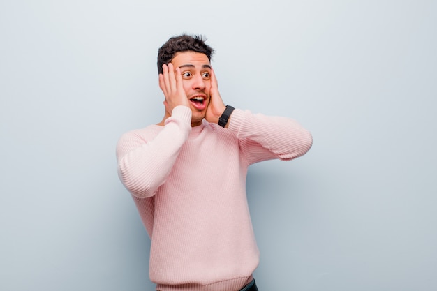 sentirsi felici, eccitati e sorpresi, guardando di lato con entrambe le mani sul viso