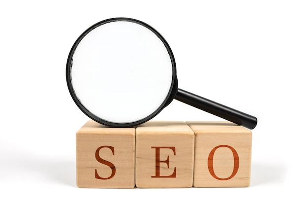 SEO ottimizzazione dei motori di ricerca testo blocchi di legno cubo e lente d'ingrandimento su bianco Idea strategia pubblicità marketing parola chiave e concetto di contenuto