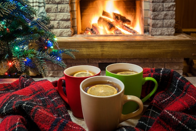 Sera di natale. Accogliente camino e tazze di tè sul tavolo di legno.