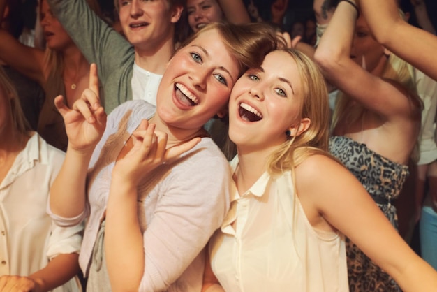 Serata di ballo rock e amici a un concerto in discoteca o esibizione di una band in mezzo alla folla Sorriso di musica da festa felice e ritratto di donne che ballano a un festival di musica rave mostrano energia e celebrazione