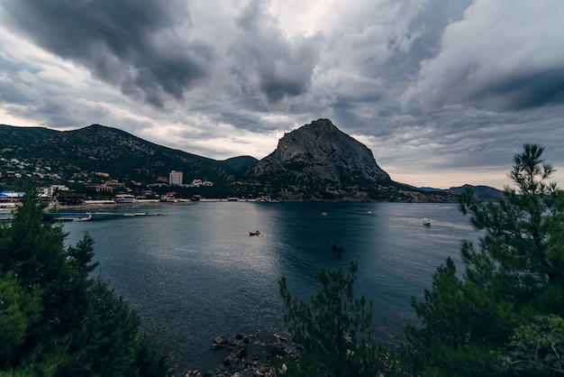 Serata nuvolosa paesaggio di mare e montagna con la città