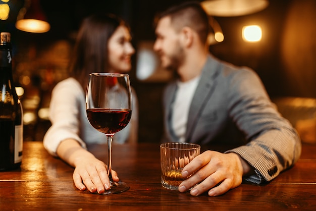 Serata romantica al bar, coppia di innamorati al bancone in legno. Gli amanti svaghi in pub, marito e moglie che si rilassano insieme in discoteca