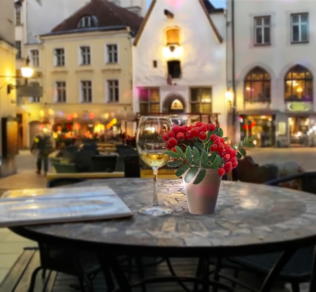 Serata street cafe bicchiere di vino e ramo di bacche di sorbo rosso sul tavolo, la gente cammina a Tallinn