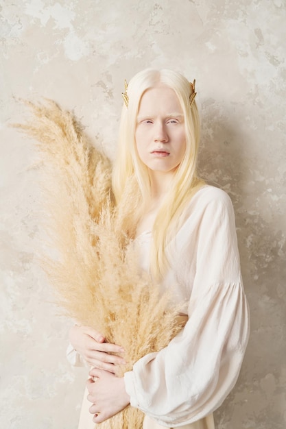 Serena ragazza albina con capelli lunghi che tengono fiori secchi