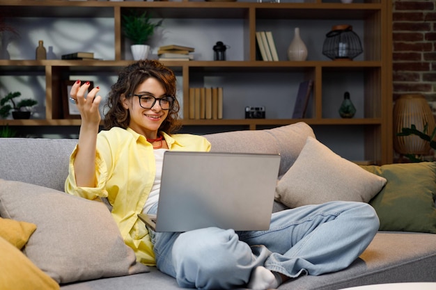 Seria giovane donna freelance che lavora come freelance da casa Lavora seduta sul divano sul laptop Ragazza focalizzata che usa il computer per studiare online a casa utente femminile Internet programmazione del lavoro remoto