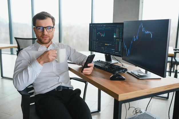 Serio analista commerciante uomo d'affari guardando il monitor del computer broker investitore analizzando gli indici grafico finanziario trading dati di investimento online sul grafico del mercato azionario criptovaluta sullo schermo del pc