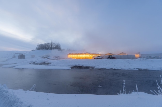 Serra islandese con luce gialla in un paesaggio innevato con vapore dei bagni termali sulle rive