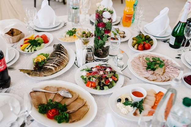 Serve la cena su un tavolo festivo Cibo Insalate Carne Pesce Pasti Tavolo festivo al banchetto di nozze Dettagli di arredamento