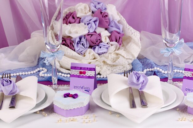 Serve un favoloso tavolo da matrimonio in colore viola su sfondo di tessuto bianco e viola