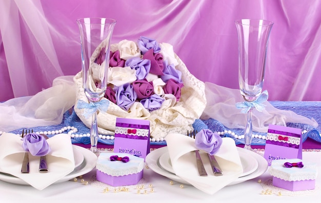 Serve un favoloso tavolo da matrimonio in colore viola su sfondo di tessuto bianco e viola