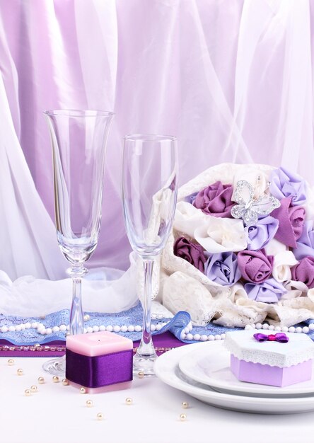 Serve un favoloso tavolo da matrimonio in colore viola su sfondo di tessuto bianco