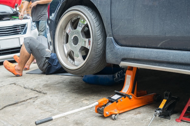 Serviceman che controlla sospensione in un&#39;automobile al garage