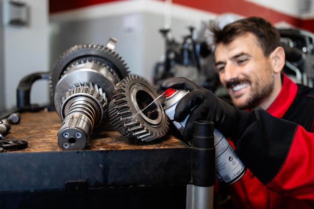 Serviziere o meccanico sorridente che ripara la scatola di marcia della trasmissione in officina