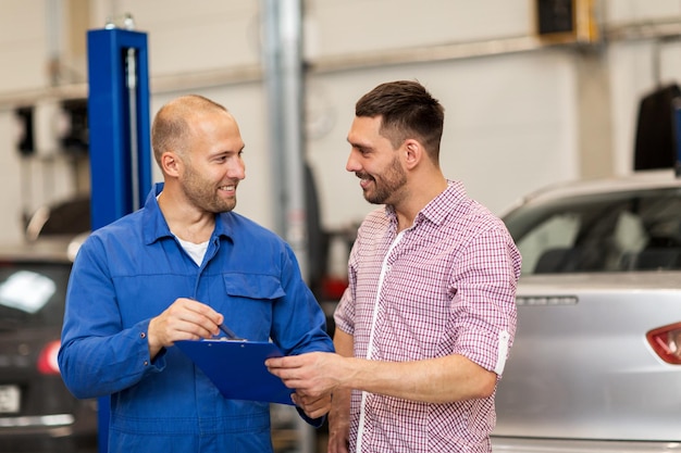 servizio auto, riparazione, manutenzione e concetto di persone - meccanico con appunti che parla con l'uomo o il proprietario al negozio di auto