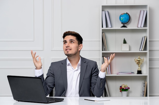 Servizio clienti carino bel ragazzo in tuta da ufficio con il computer felice e alzando lo sguardo sorridente