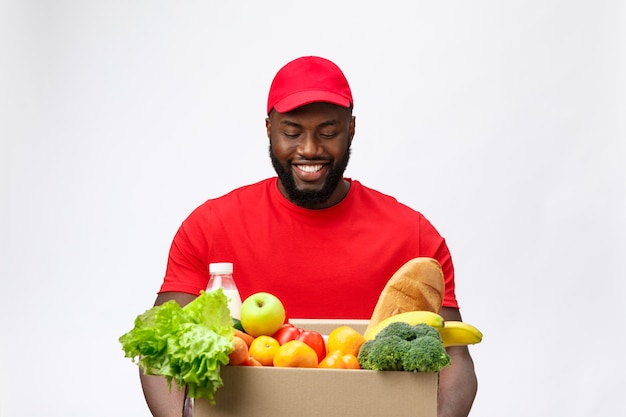 Servizio di consegna - Bello afroamericano uomo di consegna che trasportano confezione di generi alimentari alimentari e bevande dal negozio.