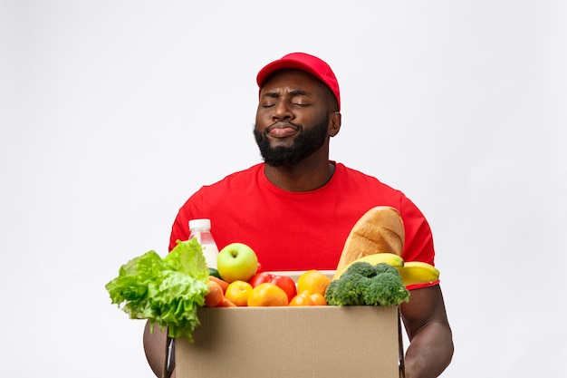 Servizio di consegna - Bello afroamericano uomo di consegna che trasportano confezione di generi alimentari alimentari e bevande dal negozio.