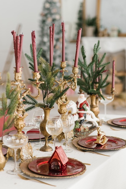 Servizio di Natale di una cena di Capodanno festivo Candele in candelieri rami di abete rosso e lastre d'oro