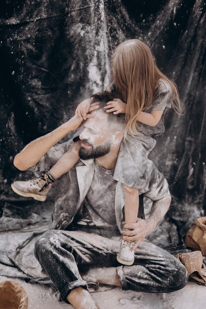 servizio fotografico di famiglia per i giovani genitori e le loro figlie su una foto in tessuto nero ambientata nella natura