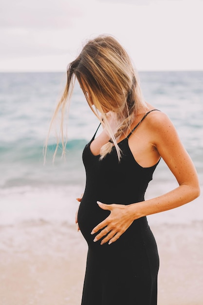 Servizio fotografico di una donna incinta che cammina sulla spiaggia