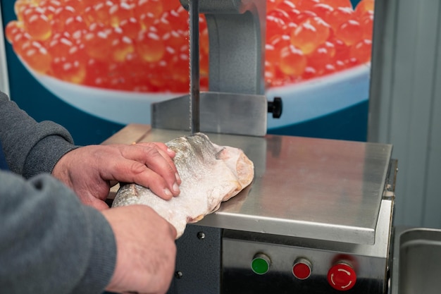 Servizio per il taglio di salmone congelato su una bistecca in un supermercato di pesce utilizzando attrezzature professionali