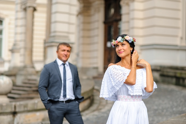 Sessione fotografica di matrimonio sullo sfondo del vecchio edificio. Lo sposo guarda la sua sposa in posa. Fotografia di matrimonio rustica o boho.