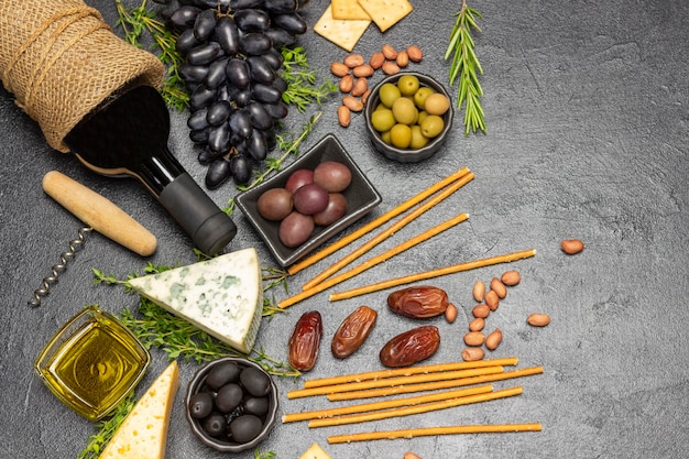 Set antipasto per aperitivo con vino rosso olive e formaggio uva e datteri baguette e crackers noci e rametti di timo