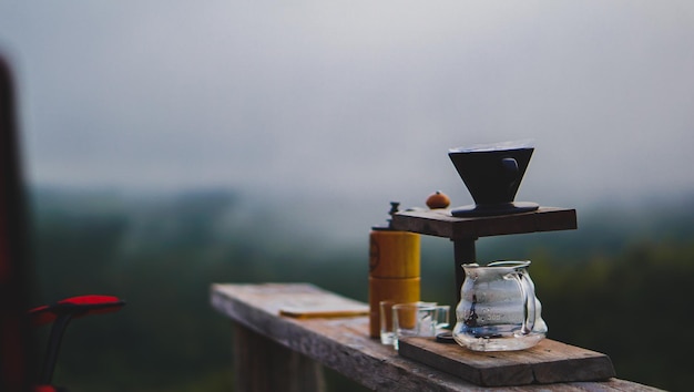 Set da caffè a goccia su tavola di legno con paesaggio di montagna su tono scuro
