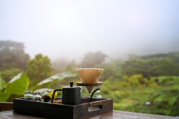 Set da caffè pourover su un tavolo di legno su una bellissima vista verde sfocata sulle montagne