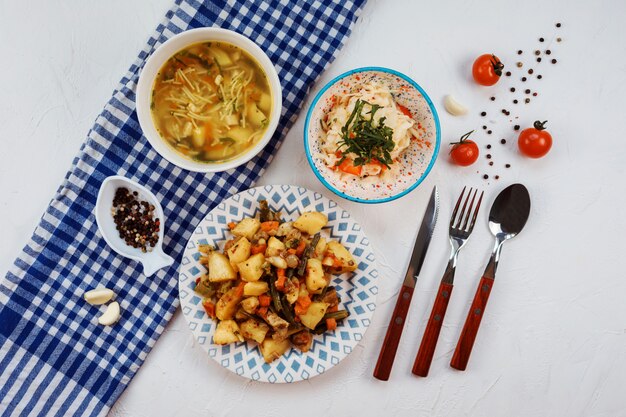 Set da pranzo composto da tre piatti sul tavolo bianco.