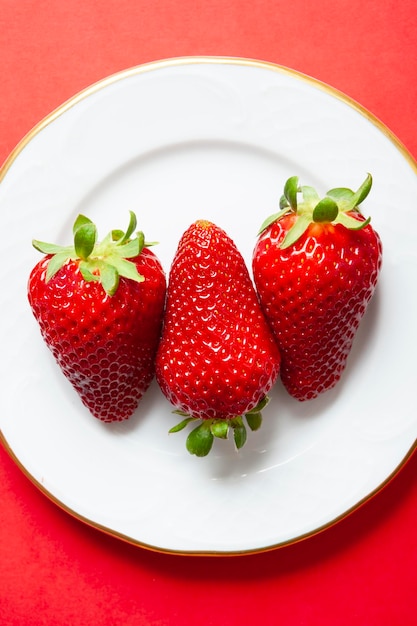 Set di 3 fragole su un piatto su sfondo rosso