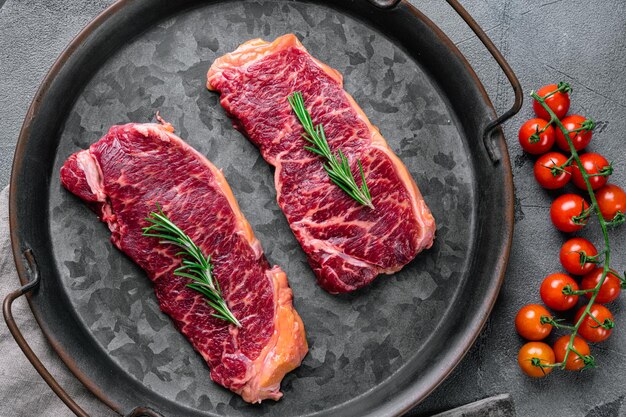 Set di bistecche di carne cruda Black Angus Prime, su sfondo grigio tavolo in pietra, vista dall'alto piatto