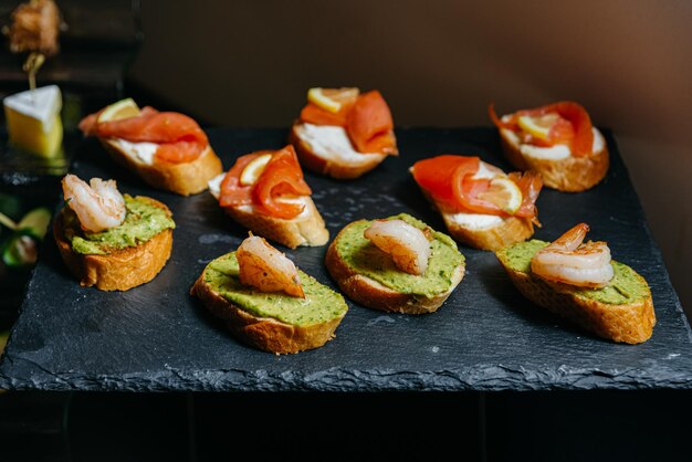 Set di bruschette con salmone e spicchi di limone, gamberi, avocado spalmabile e crema di formaggio