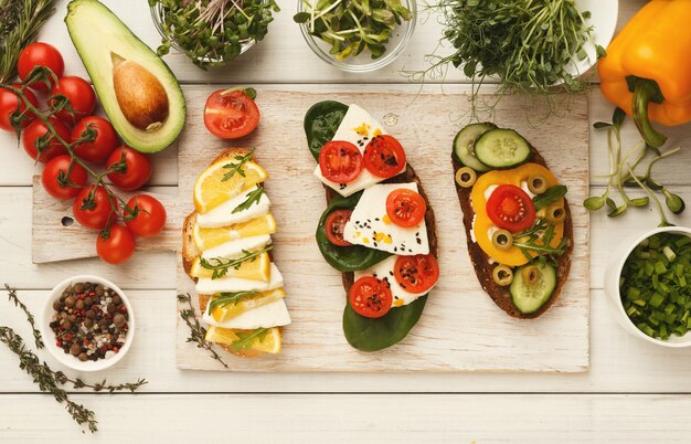 Set di bruschette sane con vari condimenti, vista dall'alto. Fare panini veretarian con formaggio morbido, verdure biologiche, spezie e verdure. Sfondo di cibo, copia spazio