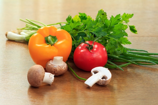 Set di buoni prodotti naturali con pepe fresco, pomodoro, funghi, cipolla e prezzemolo sul tavolo