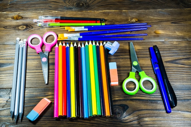 Set di cancelleria per la scuola. Matite colorate, penne, forbici, gomma, pennelli sulla scrivania in legno. Ritorno al concetto di scuola