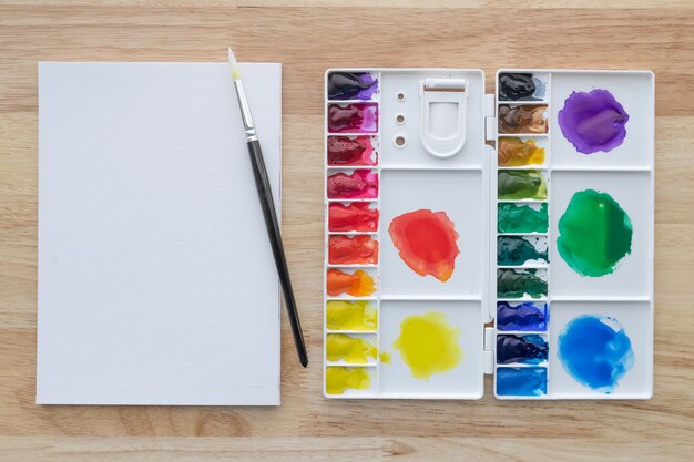 Set di colori ad acquerello con carta bianca. Vernici aquarelle multicolori luminose per sfondo artistico.