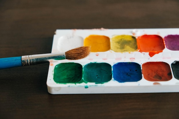 Set di colori ad acquerello con un pennello per dipingere su uno sfondo di legno scuro