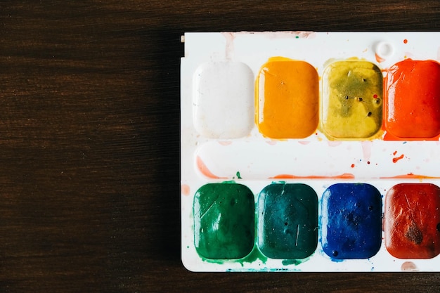 Set di colori ad acquerello su uno sfondo di legno scuro. Copia, spazio vuoto per il testo