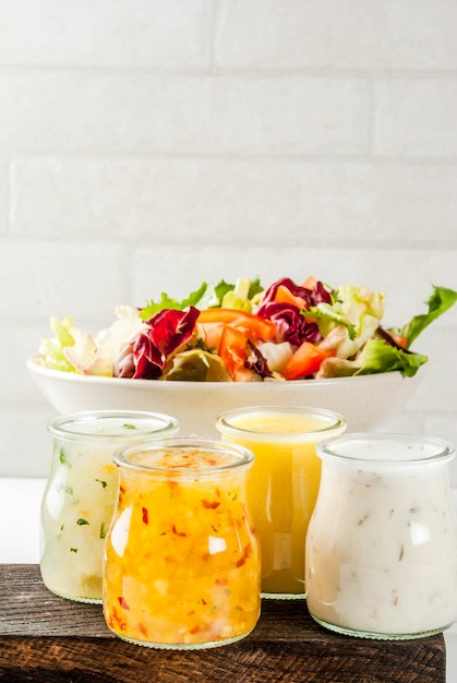 Set di condimenti per insalata classici senape di miele, ranch, vinaigrette, limone e olio d'oliva, sul tavolo di marmo bianco,