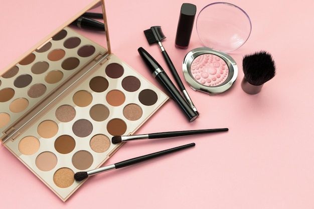 Set di cosmetici decorativi ombretti palette pennelli mascara su sfondo rosa